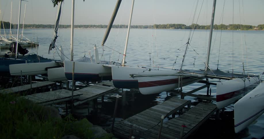 Boats are docked in the marina as sunlight reflects on the water as it ripples and moves