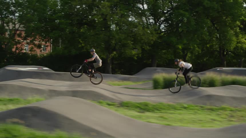 Two cyclists jumping and driving motocross bicycles on a beautiful small track