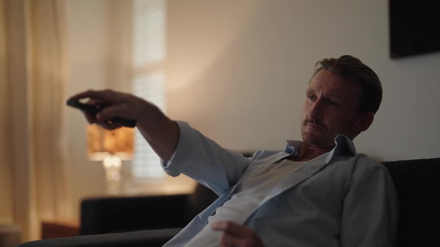 A man is sitting on a couch and watching television