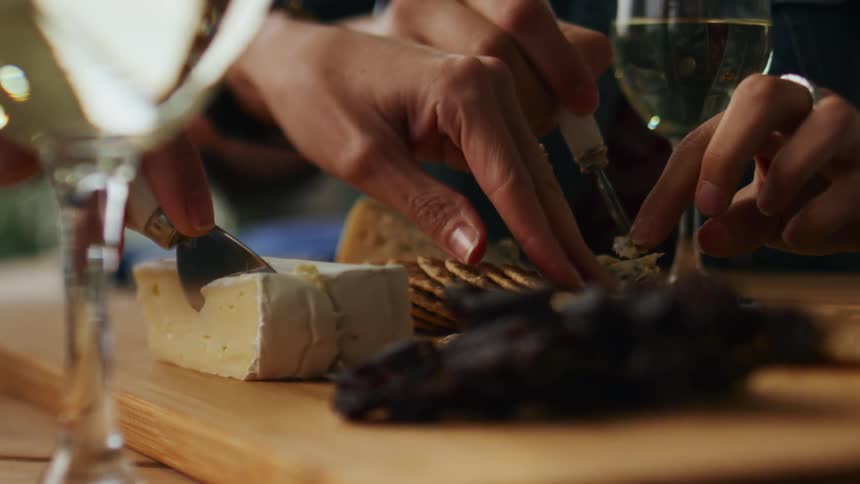Two people sitting at a table eating together from a cheese board