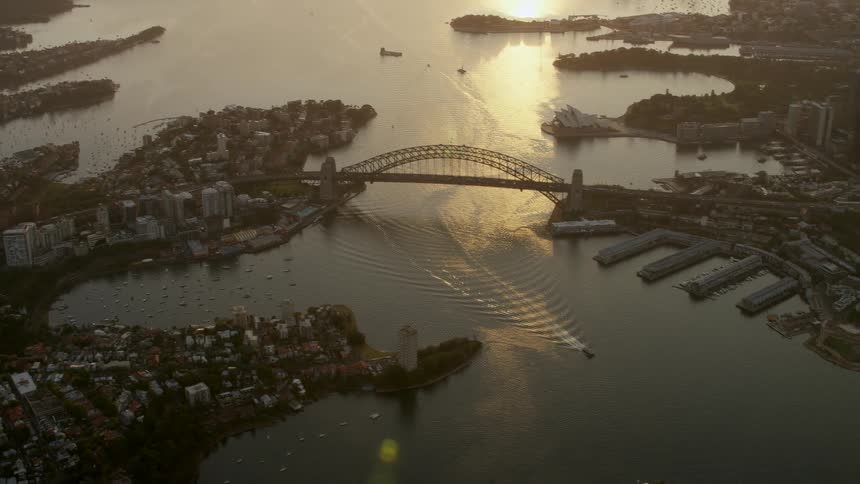 Aerial view of a boat sailing on a river through a city at evening