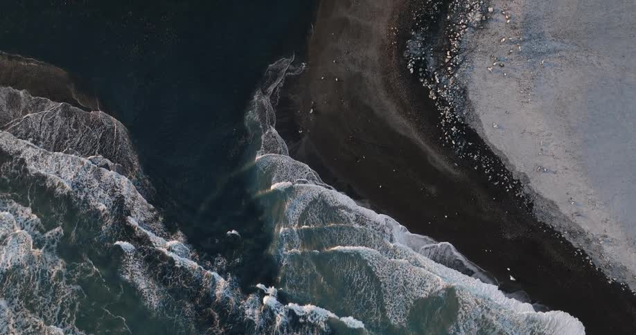 An aerial view of ocean waves flowing towards the shoreline