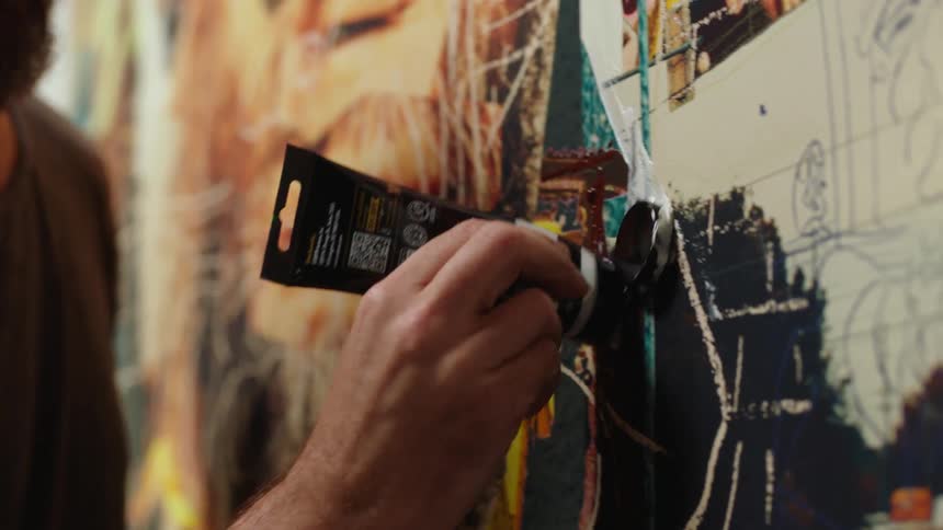 A painter is squirting a tube of paint on the canvas