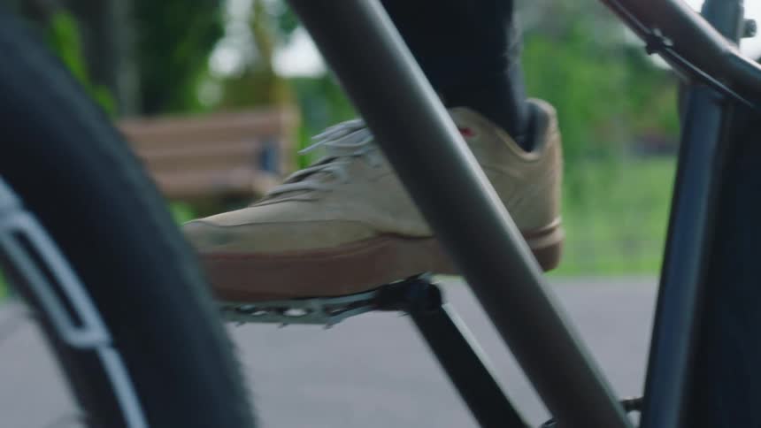 A persons feet are shown starting to ride a bike by putting their feet on the pedals and riding off