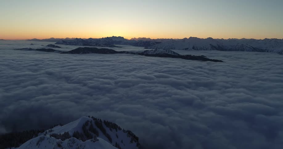 An aerial view of mountain peaks with clouds covering the land