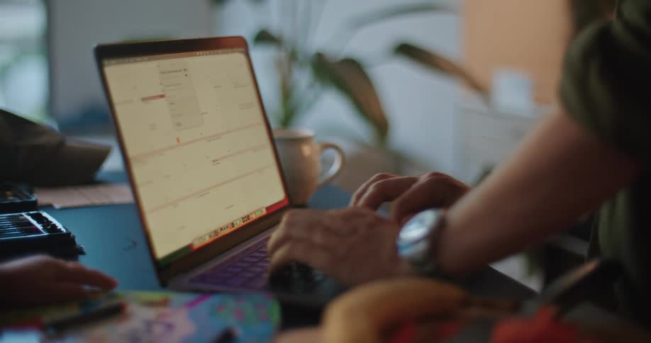 Man working on a computer near a child on the kitchen counter at home