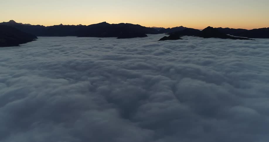An aerial view of mountain tops with clouds settling in the valley