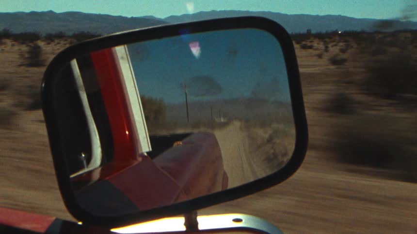 Red pickup truck drives on dirt road