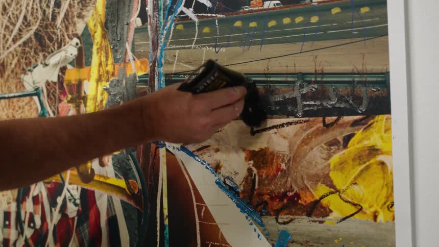 Close up of an artist painting on a large canvas with oils on the wall of a museum