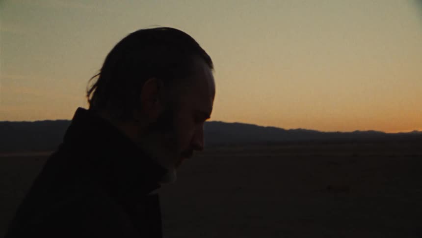 A man is smoking outdoors while the sun is setting