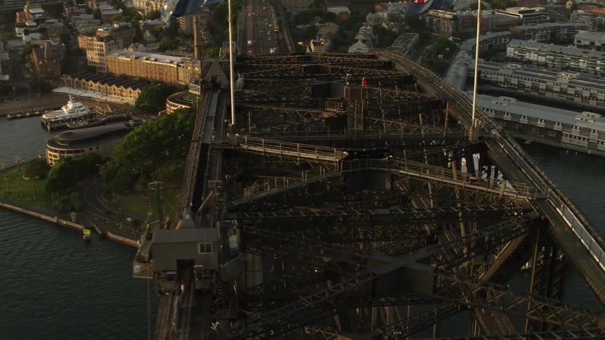 A bridge with flags on the top going over a waterway with cars traveling on it