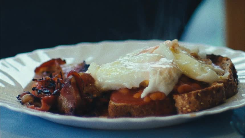 Close up of a full hot steaming breakfast on a white dish over a table