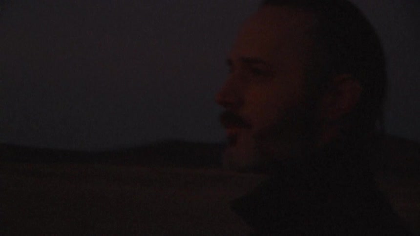 A man walking around at night appearing confused and uncertain