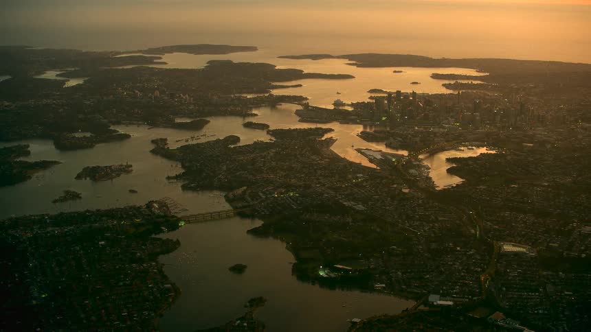 A large part of a neighborhood surrounding water is filmed with a drone in the air
