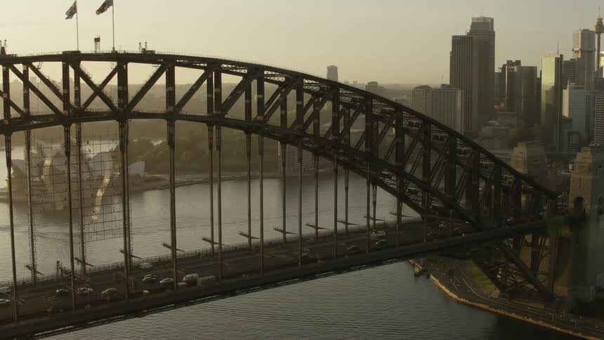 An aerial view of a metropolis with a large bridge over a waterway at sunset