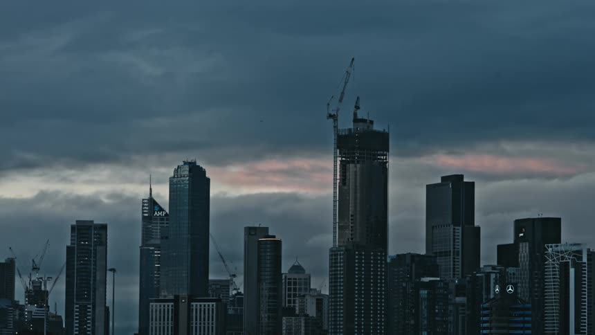Some industrial buildings are shown in a city against the evening sky