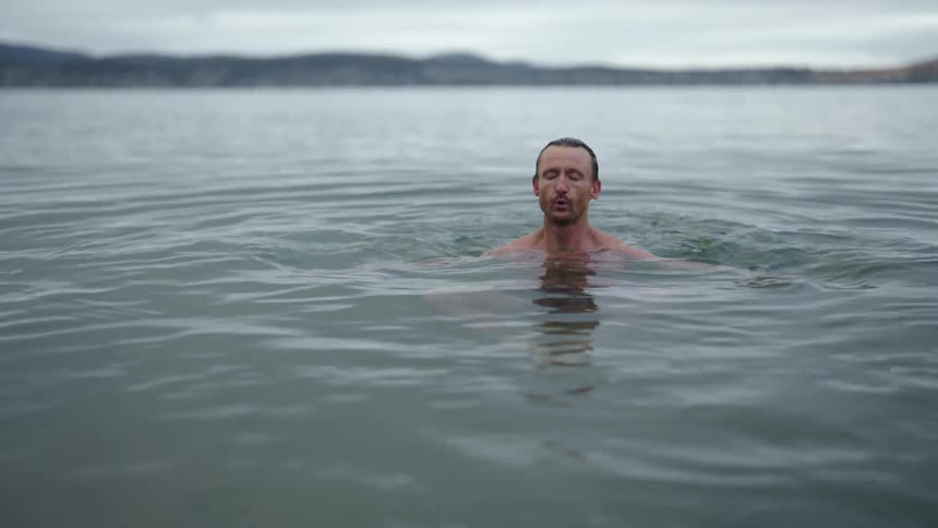 A man ducks his head underwater while swimming in the ocean