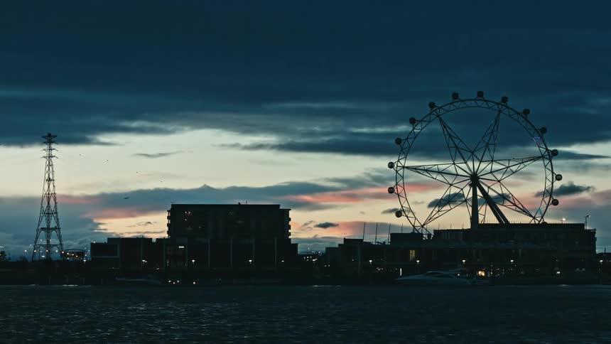 A silhouette of a ferris wheel against a dusk sky