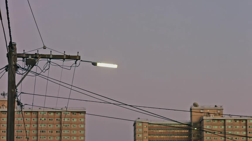 The tops of a few buildings are shown against a blue sky with power lines in front