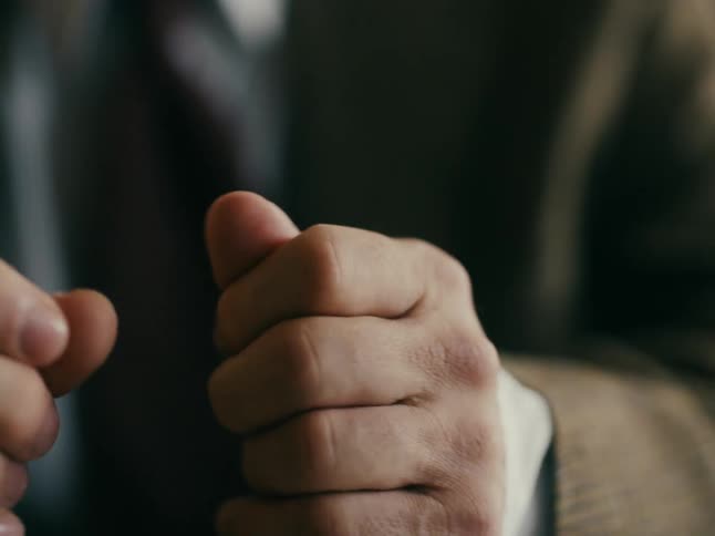 Man wearing suit fidgets with his hands