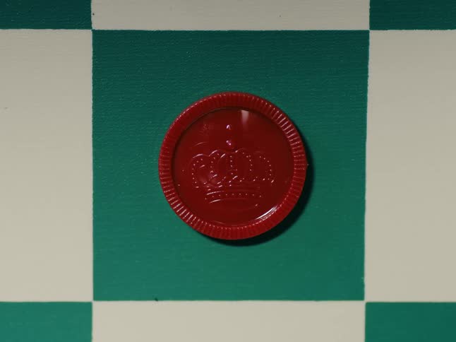 A red checker piece sits on a green square on the checker board