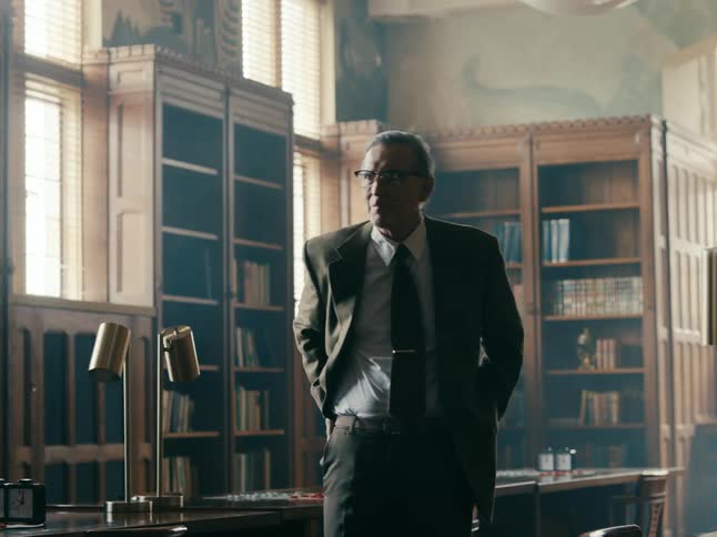A man is walking around a room and wearing a suit