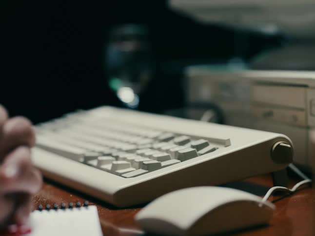 A hand typing something on the keyboard and using a mouse