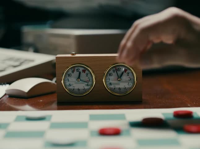 Two men play chess using an analog countdown clock