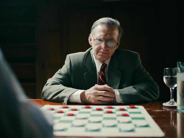 Two men are sitting across from each other playing a game of checkers
