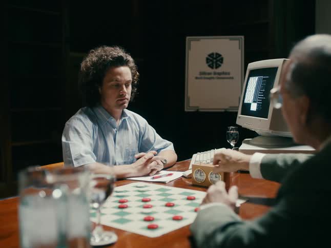 Older man makes move in checker game and stops clock then second man records move on old desktop