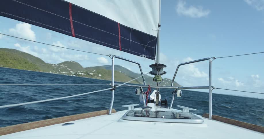 The sail of a sailboat moves in the wind as it sails across the water