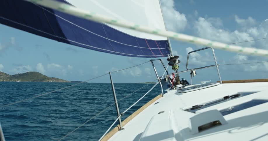 The sail of a sailboat moves in the wind as it sails across the water
