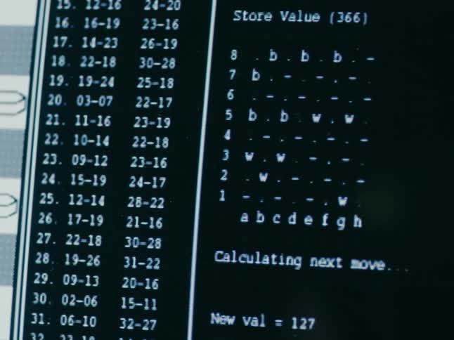 Computer monitor displays black and white text and checker game board as computer calculates its moves