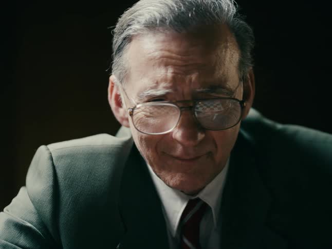 Close up of the face of an elderly gentleman on a suit playing checkers