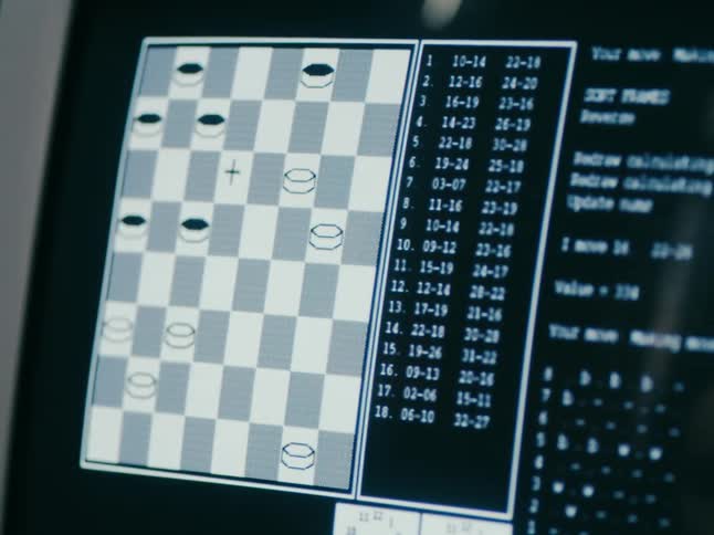 Old computer monitor displaying checker board and game reflects face