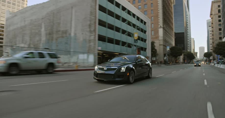 A car travels along a road through a metropolis during the day