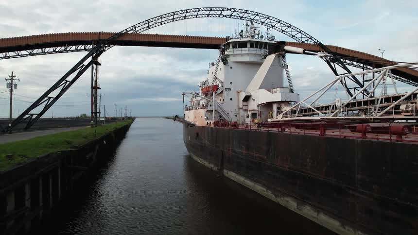 A very large boat slowly goes under a bridge and an archway