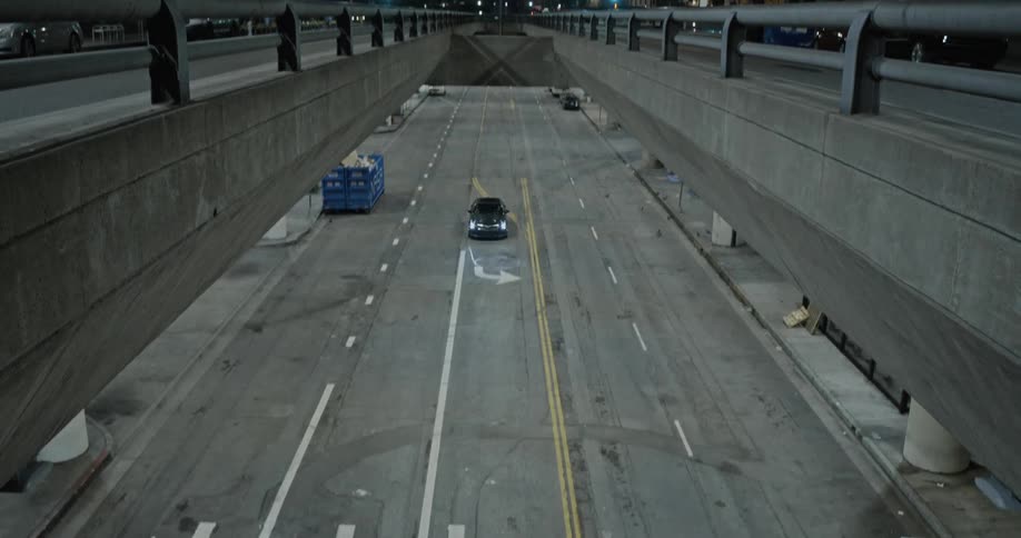 A car driving on a road under and overpass at night in the city