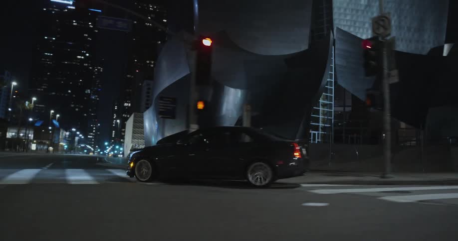 Black car driving on the city street at night