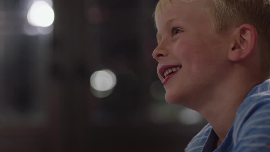 A little boy is talking to someone off camera and smiling