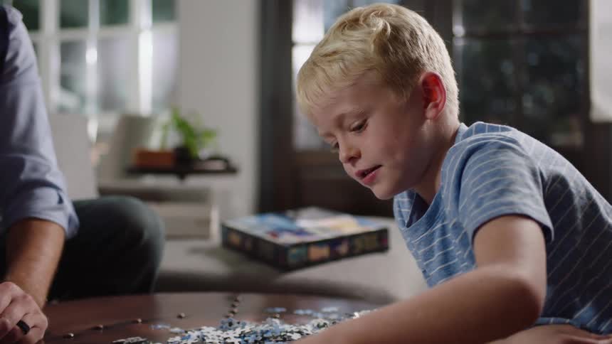 Boy building a puzzle on coffee table near his father