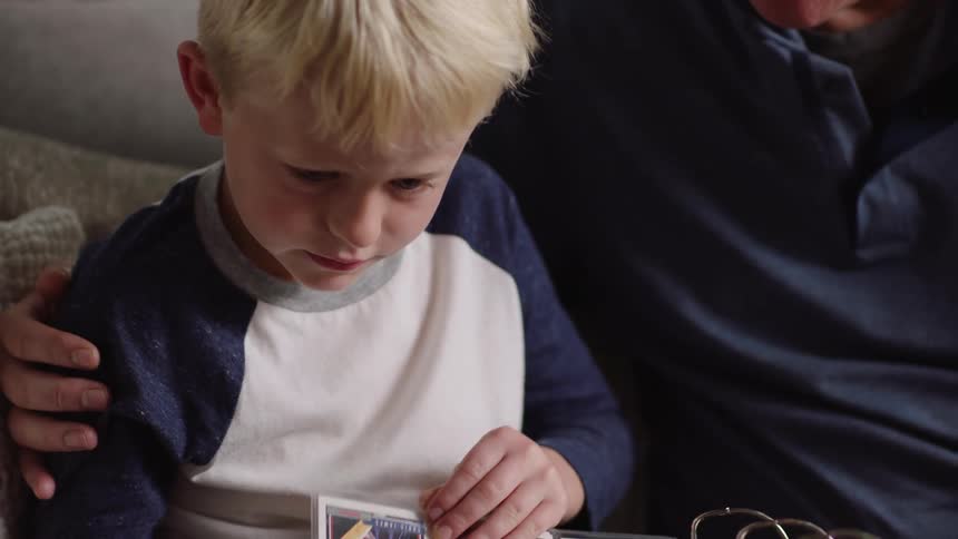 A man high fives his son while going through an album of baseball cards