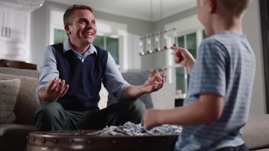 Father and son assembling a puzzle in the living room at home