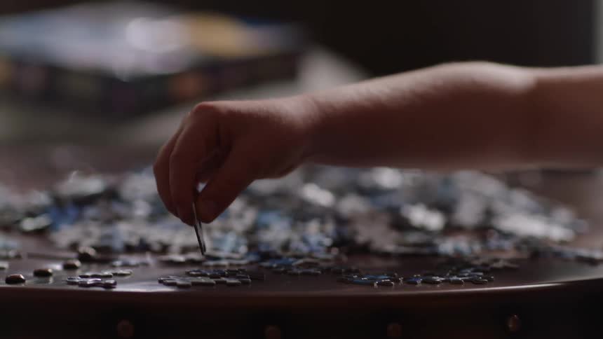 Person puts puzzles together at table