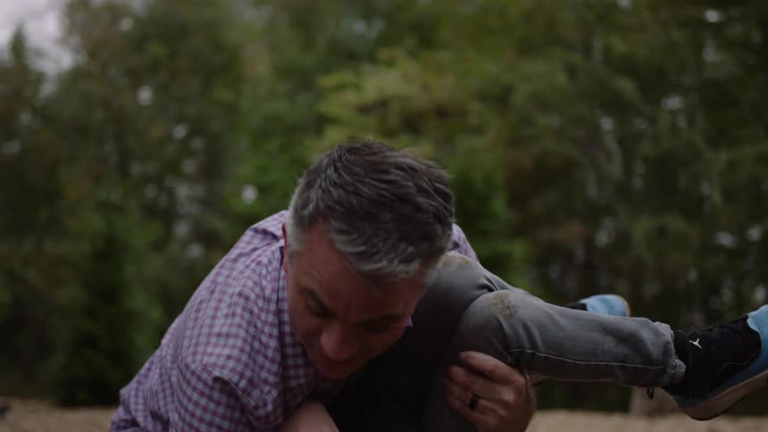 Father playfully holds his son on his arms while playing in the backyard