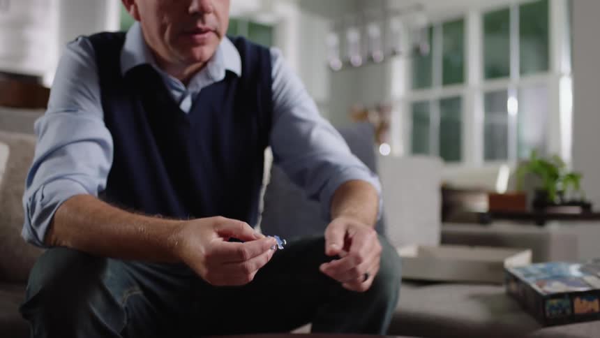 Father with blue shirt and vest do puzzles with son in living room at home