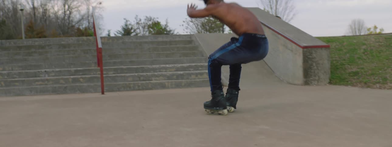 Man on inline skates jumps down flight outdoors in park