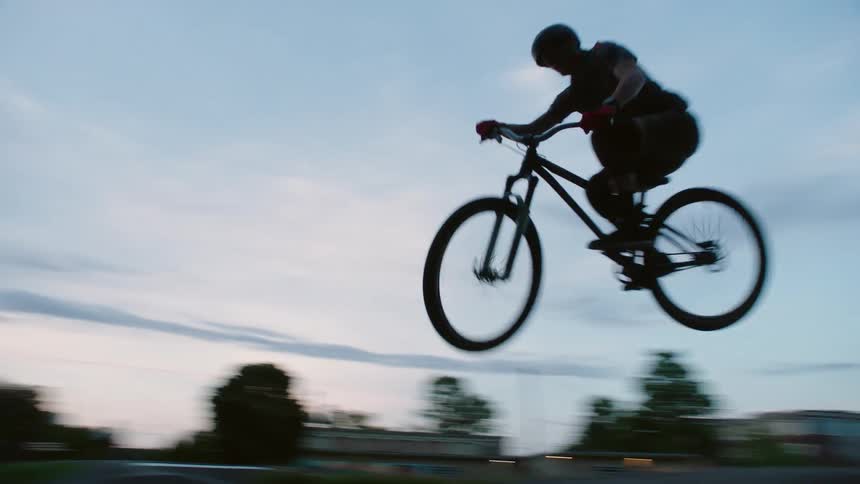 A person riding a bike and going over a jump in a park
