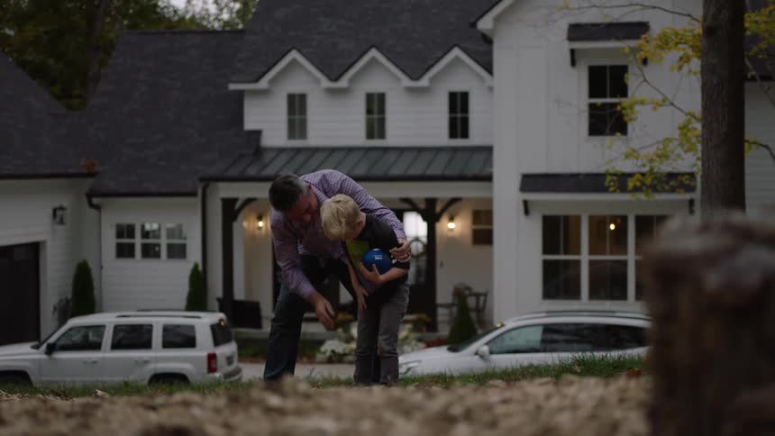 Father and son playing football on the yard in the neighborhood