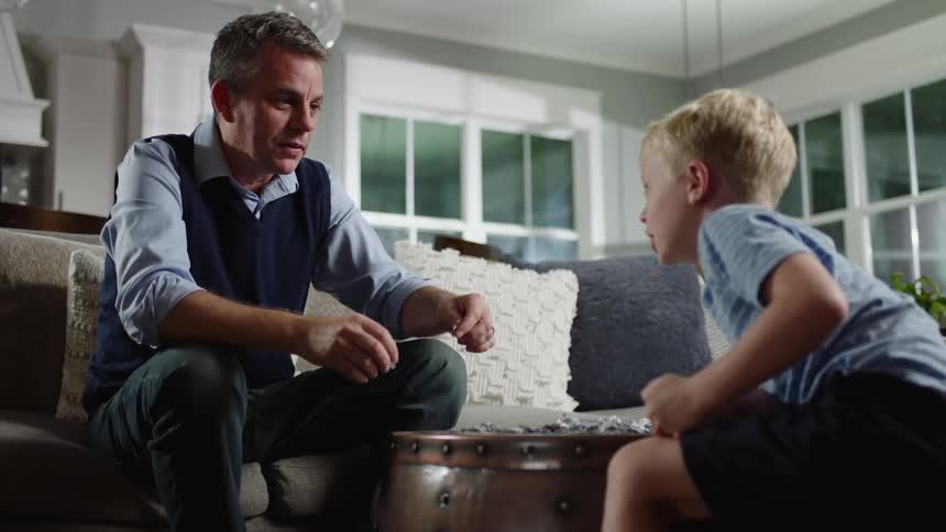Father and son are enjoying putting together a jigsaw puzzle on a table in a living room